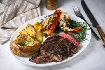 surf and turf, ribeye steak and lobster tail on white marble background