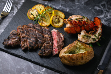 surf and turf, ribeye steak and lobster tail on black marble background