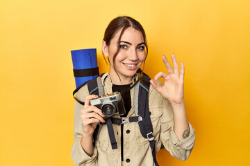 Photographer with gear ready to explore cheerful and confident showing ok gesture.