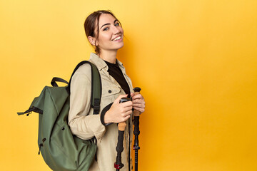 Caucasian woman with backpack and hiking sticks, yellow - Powered by Adobe