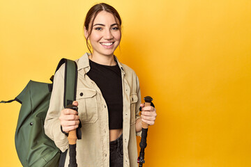 Caucasian woman with backpack and hiking sticks, yellow