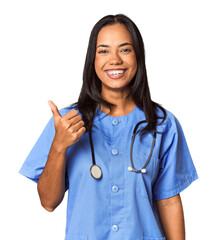 Young Filipina nurse posed in studio smiling and raising thumb up