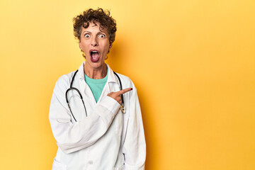 Caucasian mid-age female doctor on yellow studio pointing to the side