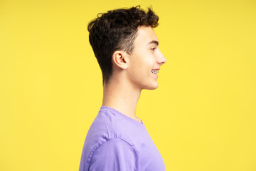 Side view portrait of attractive positive teenage boy with dental braces looking away