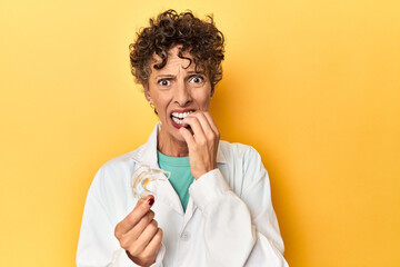 Doctor with invisible dental aligner on yellow biting fingernails, nervous and very anxious. - Powered by Adobe
