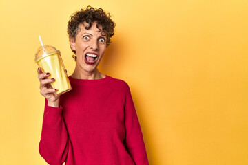 Woman sips a vanilla shake on a vivid yellow studio background