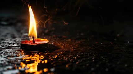Close-up of a candle flame on a dark wet surface