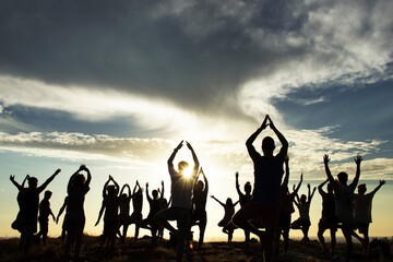 Silhouette of an outdoor yoga class at sunset 
