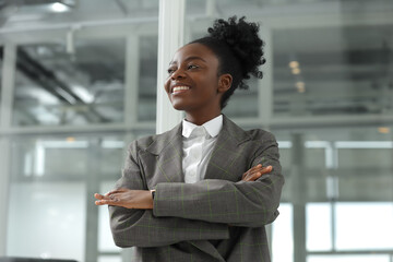 Happy woman with crossed arms in office, low angle view. Lawyer, businesswoman, accountant or...