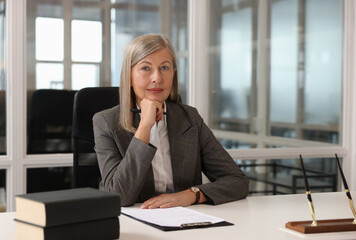 Smiling woman at table in office. Lawyer, businesswoman, accountant or manager