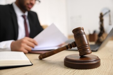 Lawyer working with document at table in office, focus on gavel