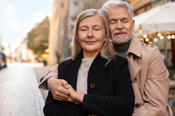 Portrait of affectionate senior couple on city street, space for text
