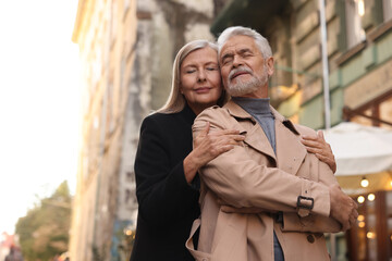 Portrait of affectionate senior couple on city street, low angle view. Space for text