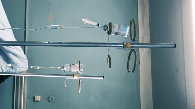 Medical infusion stands with a dropper bottles and a IV with a drip chambers in a observation ward. Intravenous injections, medical care in a clinic or hospital. Recovering patients. Vertical video