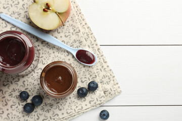 Tasty baby food in jars and ingredients on white wooden table, flat lay. Space for text