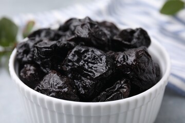 Sweet dried prunes in bowl on table, closeup