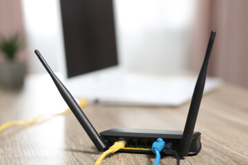 New modern Wi-Fi router on wooden table indoors