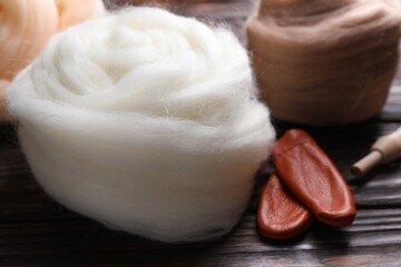 Colorful felting wool and finger protectors on wooden table, closeup