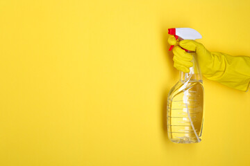 Woman holding plastic spray bottle on yellow background, closeup. Space for text - obrazy, fototapety, plakaty