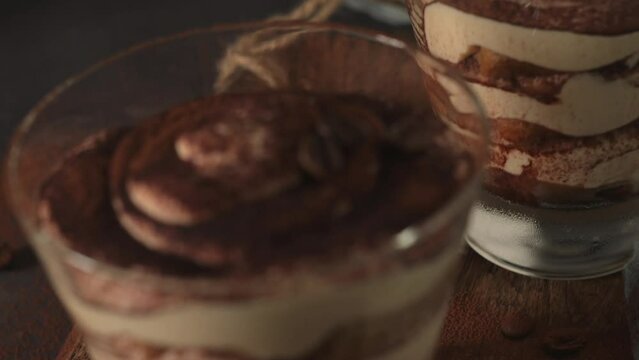 Delicious italian dessert tiramisu in a glasses on a dark slate, stone or concrete background.
