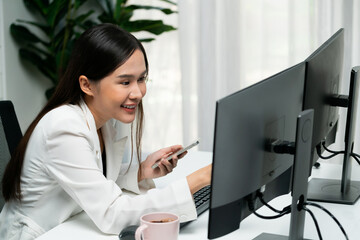 Smiling young Asian businesswoman searching marketing online strategy using smartphone to analyze...