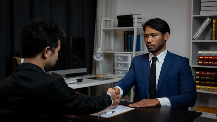 Close-up of two businessmen shaking hands and greeting each other in a conference room in the...