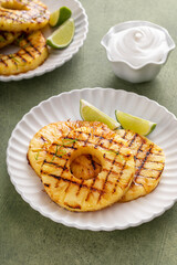 Grilled pineapple served with fresh lime wedges and whipped cream