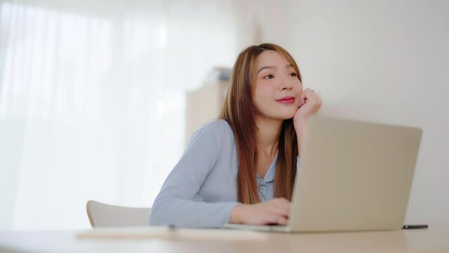 Young asian woman working at home. Happy female using computer laptop on desk at house