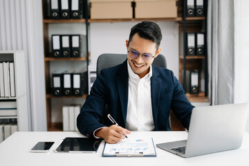 Attractive Asian male office worker business suits smiling at camera in office