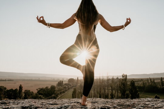 Fitness woman. Well looking middle aged woman with long hair, fitness instructor in leggings and tops doing stretching and pilates on the rock near forest. Female fitness yoga routine concept.