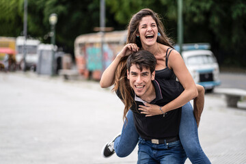 Fototapeta premium Boyfriend carrying his girlfriend on piggyback. Funny and happy expression