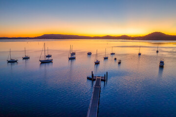 Aerial sunrise over the calm water with boats - obrazy, fototapety, plakaty
