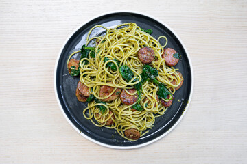 A plate of pesto spaghetti with chorizo.