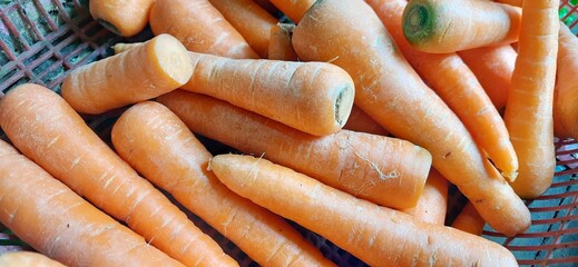 Close up of heap raw carrots placed on stall of market ready to sold. Carrot background