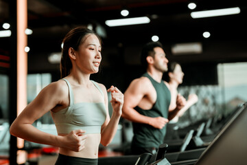 Fototapeta na wymiar Fit young woman and man running on a treadmill during a workout class at fitness gym
