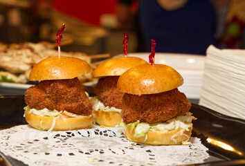 A trio of croquette sliders sit on a lace doily at an outdoor cafe. - obrazy, fototapety, plakaty