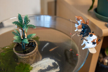 メダカのいる金魚鉢に置かれた釣りをする猫のフィギュア