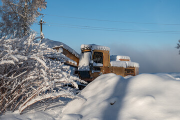 Excavator covered with snow at a construction site.
