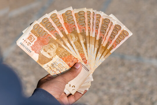 boy holding pakistan currency notes worth of five thousand rupees in hands