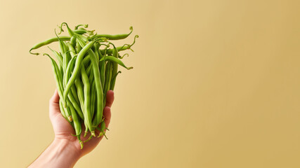 Obraz premium Hand holding green bean vegetable isolated on pastel background
