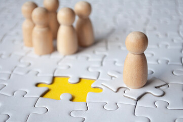 Wooden doll on top of jigsaw with missing jigsaw puzzle. Hiring and employment concept