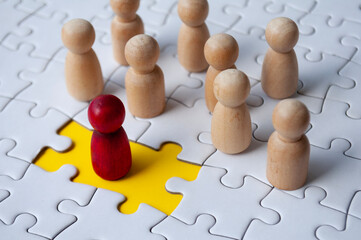 Wooden dolls on top of jigsaw with missing jigsaw puzzle. Hiring and employment concept