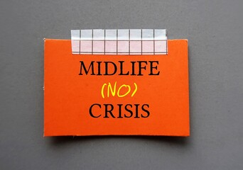 Red card stick on wall with handwritten text MIDLIFE NO CRISIS - to overcome crisis on transition...