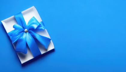 Flatlay of Valentines Day white giftbox with blue ribbon on blue background with copyspace
