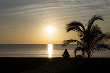 Meditating on a beach at sunrise