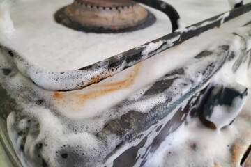 Cleaning a gas stove with a powerful product, the foam of which washes away all dirt from all surfaces. Household chores and means to keep the house clean