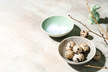 Plate with Easter quail eggs, bunny and branch on grey grunge background