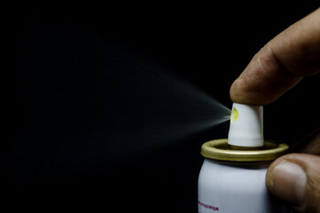 Close up view of a man spraying, A spray can  in a hand on a black background