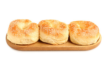 Wooden board of tasty bagels with sesame seeds on white background