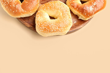 Plate of tasty bagels with sesame seeds on beige background, closeup